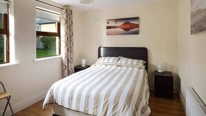 Une chambre à coucher avec un lit, une fenêtre, une chaise et un tableau accroché au mur.