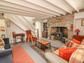 Un salon chaleureux avec une cheminée en pierre, un fauteuil en bois, un canapé et une table à manger.