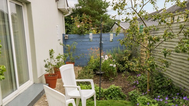 A garden with a white chair, potted plants, and a blue fence. - 2 Castle Cove (Dromahair)
