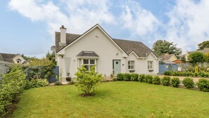 A single-story house with a sloped roof, a front porch, and a small front yard with a tree and shrubs. - 2 Castle Cove (Dromahair)