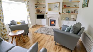 A living room with a fireplace, grey sofas, wooden flooring, and a television. - 2 Castle Cove (Dromahair)