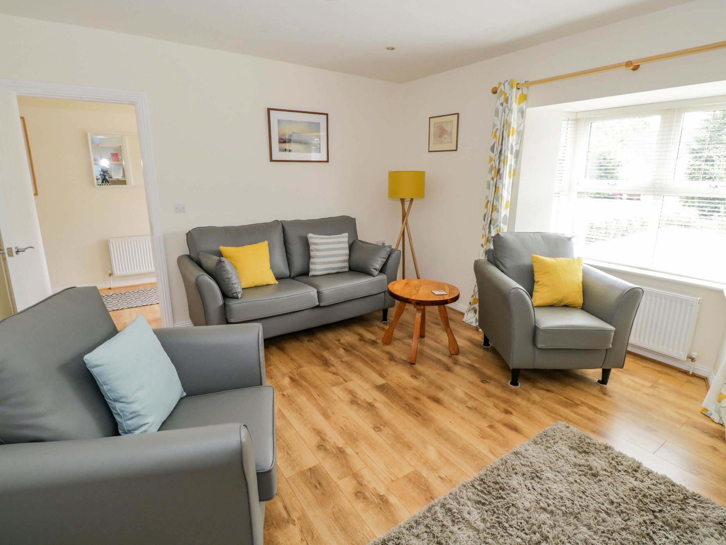 A living room with a grey sofa, a grey armchair, a small wooden table, and a floor lamp.