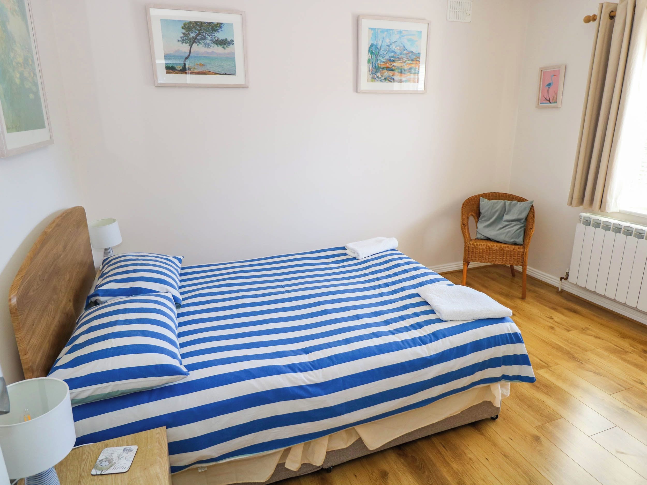 Une chambre à coucher avec un lit, une chaise et deux tableaux encadrés accrochés au mur.