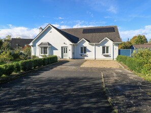 A two-story house with a sloped roof, a front entrance, and a driveway leading to the front door. - 2 Castle Cove (Dromahair)
