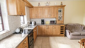A kitchen with wooden cabinets, a microwave, a kettle, and a coffee maker. - Belladrihid Cottage (Ballysadare)