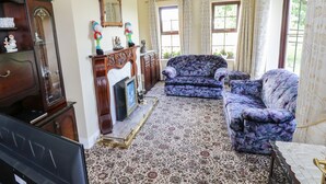 A room with a fireplace, two sofas, a TV, and a chandelier. - Belladrihid Cottage (Ballysadare)