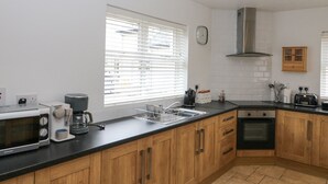 A modern kitchen with wooden cabinets, a microwave, a kettle, and a toaster. - Rock Lawn Cottage (Drimoleague)