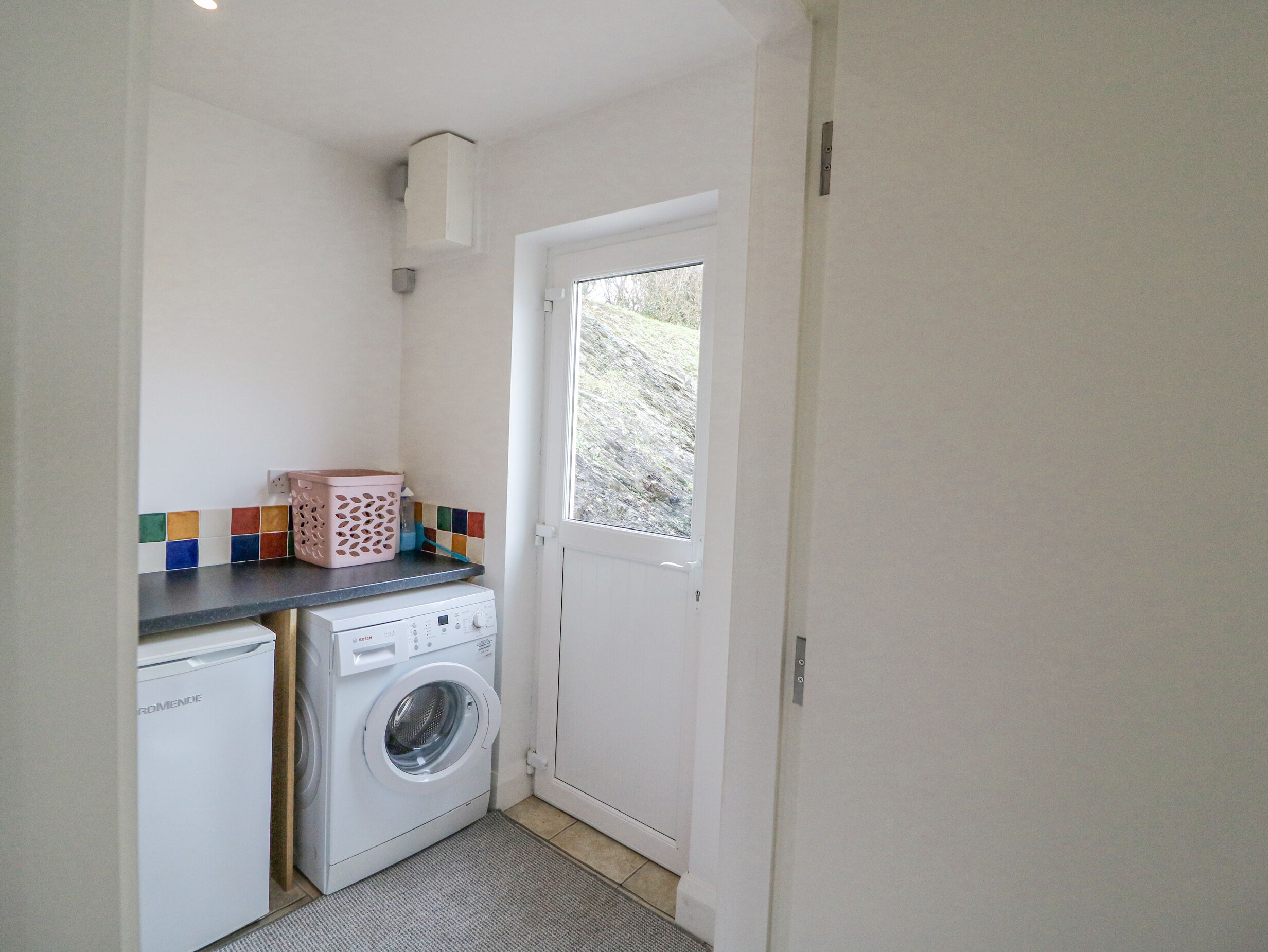 A compact laundry room with a washing machine, a dryer, and a small window.
