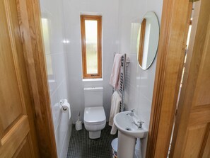 A small, clean bathroom with a toilet, sink, and a window. - Blue Stack House (Letterbarrow)