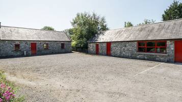 A courtyard with two stone buildings, each with a red door and window frames.