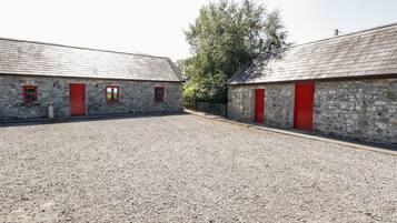 A gravel courtyard with two stone buildings, each with a red door and window.