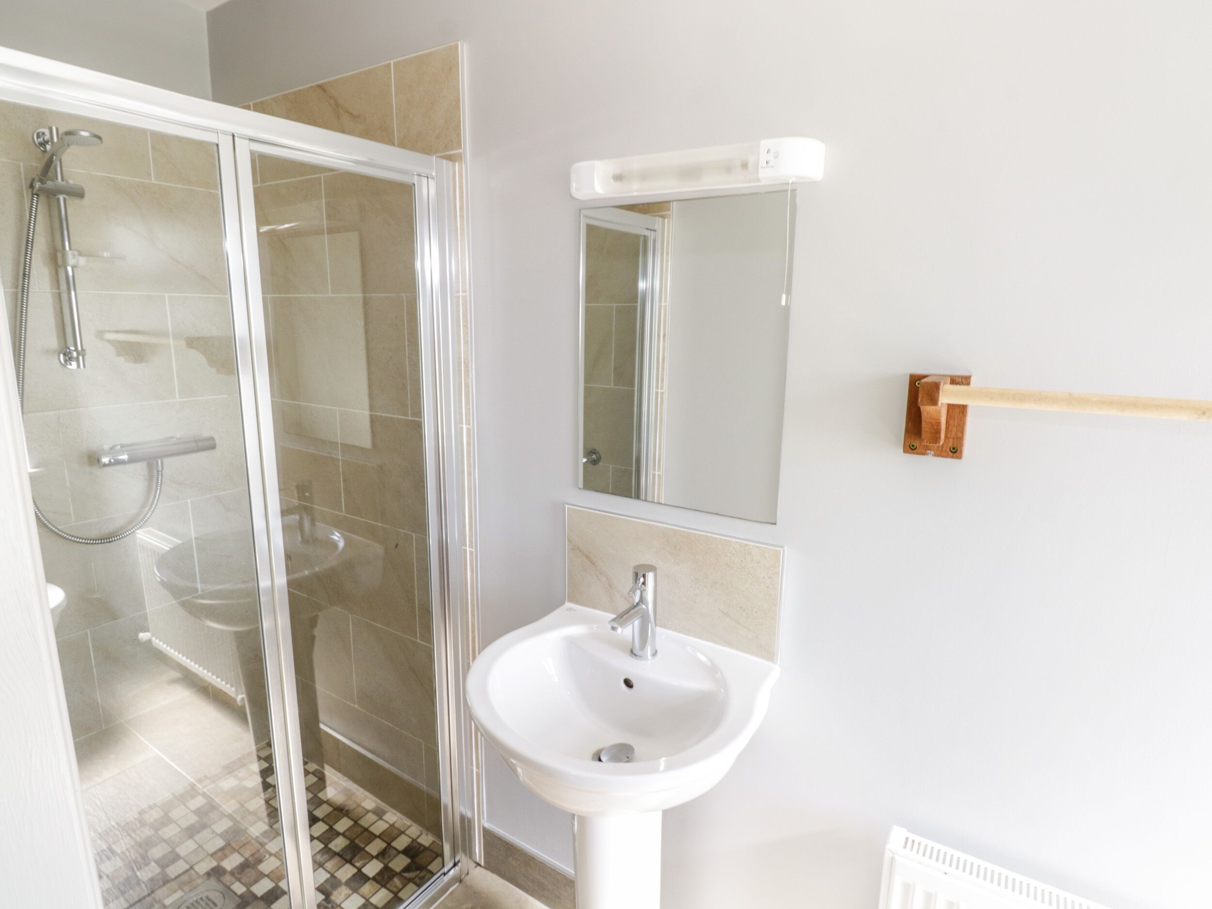 Une salle de bain avec une douche à parois de verre, un lavabo blanc et un miroir.
