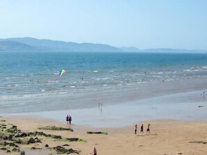 A beach with people walking and playing, and a colorful kite flying. - The Beach House Apartment (Buncrana)