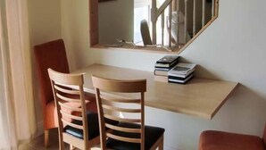 A dining area with a wooden table, two chairs, and a mirror above the table.