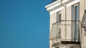 A corner of a building with a balcony featuring a metal railing.