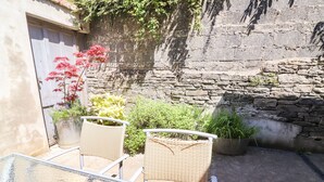 A glass table with wicker chairs in a courtyard with stone walls and potted plants. - The Merchant's Store (Kilrush)