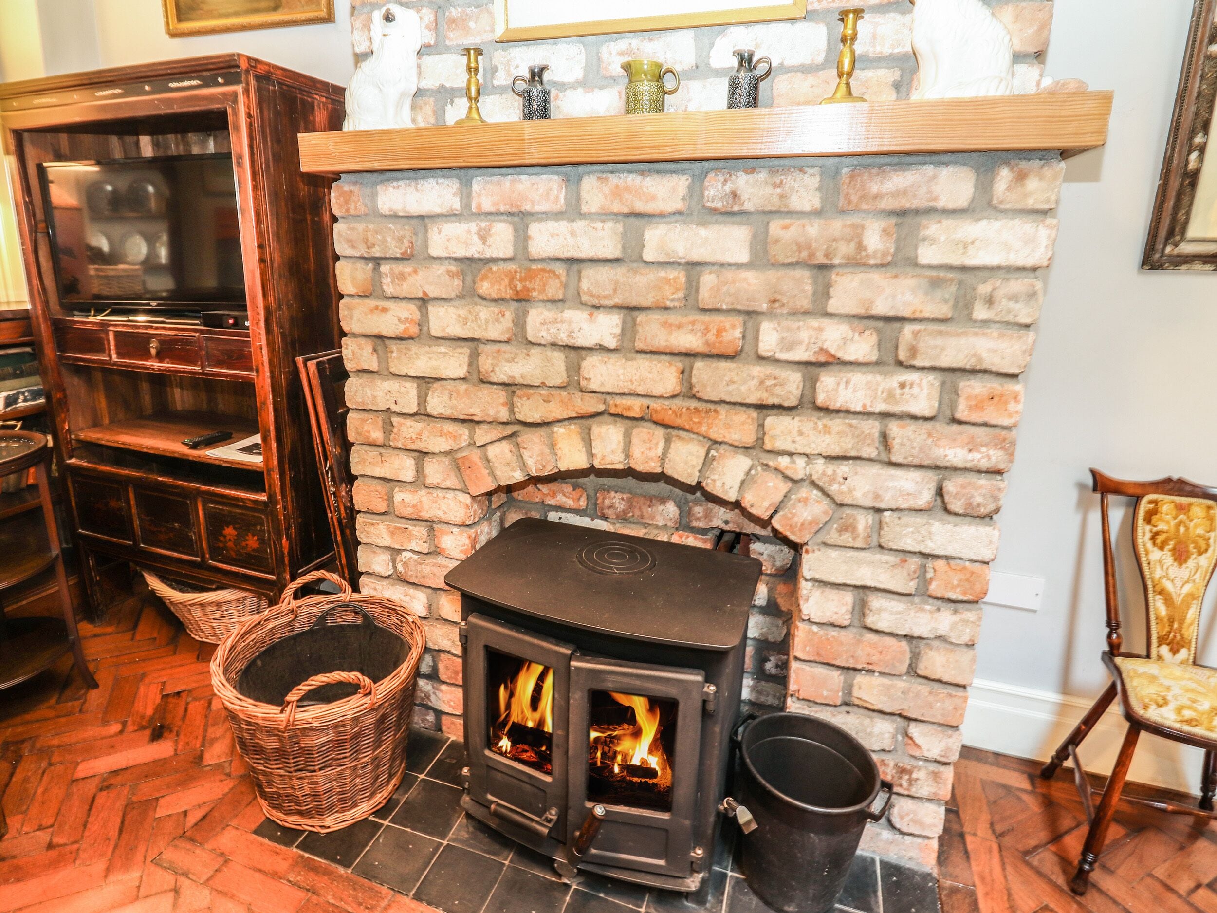 A cozy room with a brick fireplace, a wooden bookshelf, and a wicker basket.