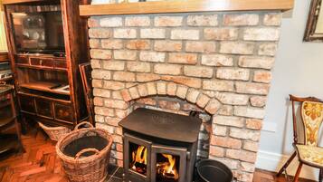 A cozy room with a brick fireplace, a wooden bookshelf, and a wicker basket.