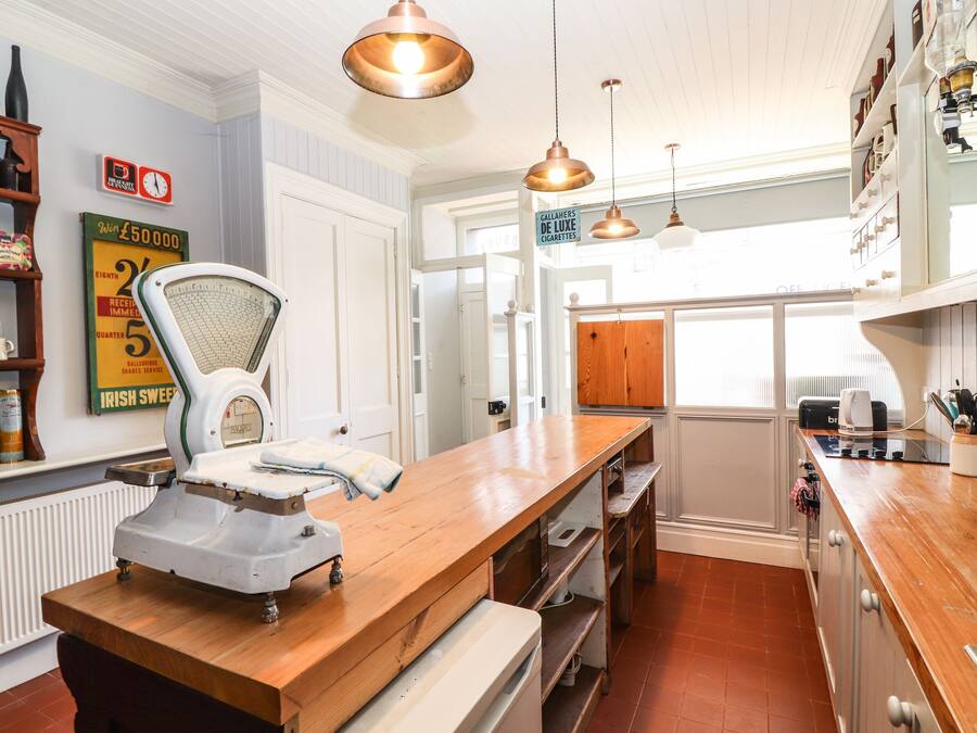 A kitchen with wooden countertops, a weighing scale, pendant lighting, and a view of the outside.