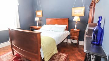 A bedroom with a wooden bed, two bedside tables with lamps, a blue wall, and a red rug.
