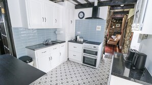 Une cuisine de taille réduite avec des meubles blancs, un plan de travail noir et un carrelage décoratif.