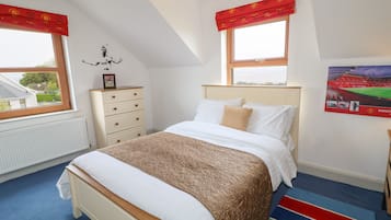 A bedroom with a bed, a dresser, a radiator, and a window with a view of the outside.