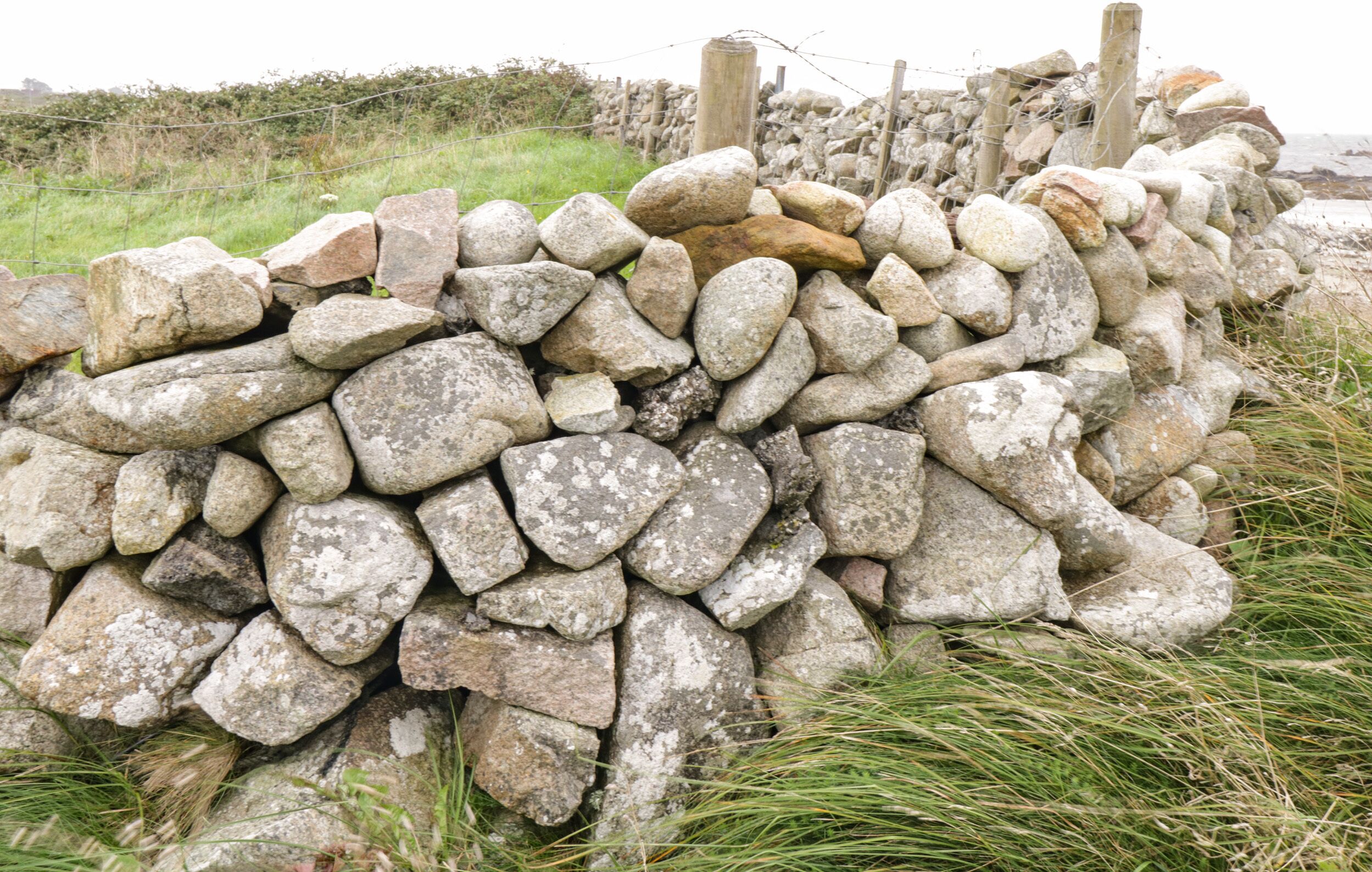 A stone wall with a wooden post and wire fence.