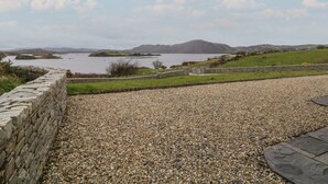 A gravel path leading to a stone wall overlooking a lake with a distant mountain. - Ranny Roe (Maghernalaght)