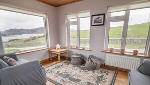 A cozy room with a large window, a star-shaped light, a small table, and a patterned rug. - Ranny Roe (Maghernalaght)