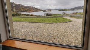 A view of a lake with mountains in the background, a stone wall, and a gravel path leading to a dock. - Ranny Roe (Maghernalaght)