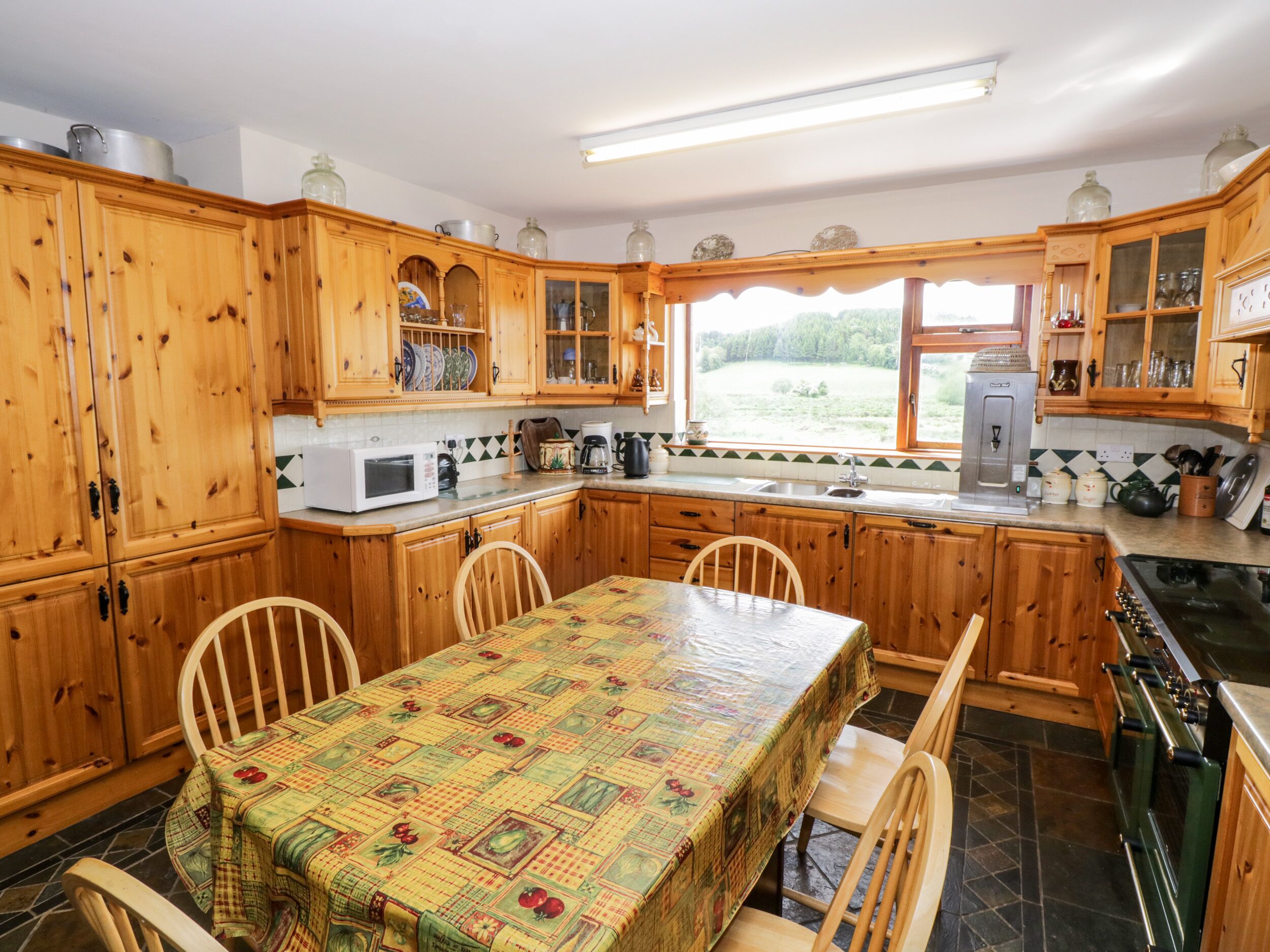 Una cocina de madera con una mesa de comedor, sillas, microondas, cafetera y estufa.