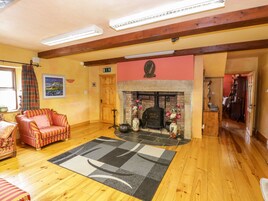 A cozy living room with a fireplace, wooden beams, a sofa, and a rug.