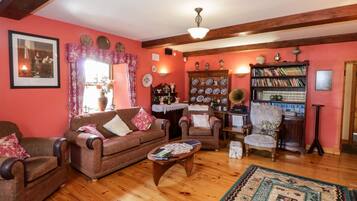 Un salón acogedor con suelo de madera, un sofá marrón, una mesita de centro pequeña y una estantería llena de libros y adornos.