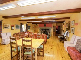 A spacious room with a wooden dining table, chairs, a sofa, and a fireplace.