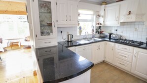 A kitchen with white cabinets, a black countertop, and a window. - Teach Teolai (Carraroe)