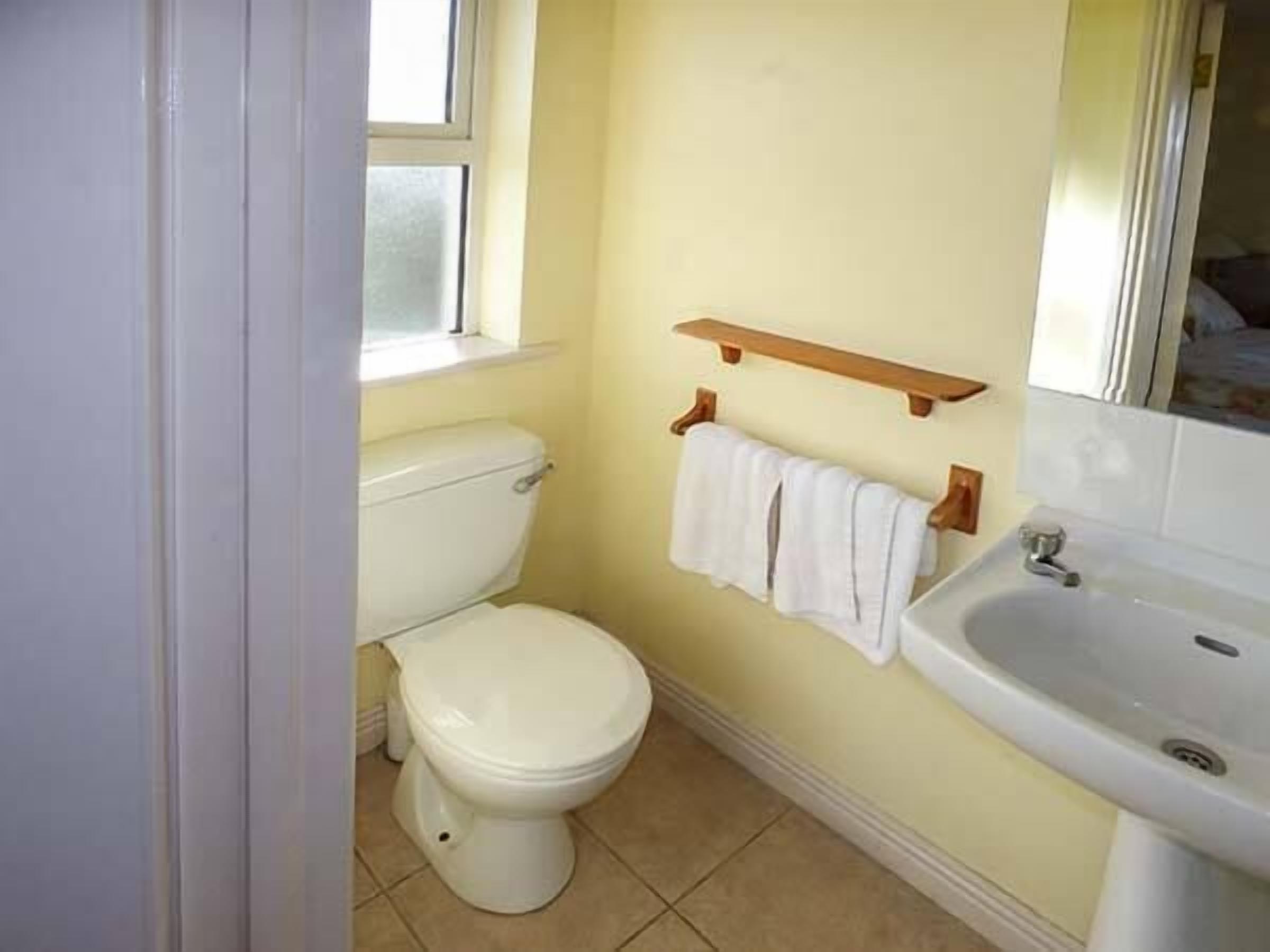 A small bathroom with a toilet, sink, and a window.