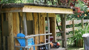 Een houten bouwvorm in rustieke stijl met een veranda, een fiets en een scooter.
