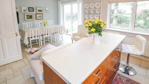 Una cocina luminosa con una isla central, armarios blancos y un comedor con sillas y mesa.