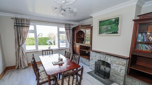 A dining area with a wooden table and chairs, a fireplace, and a bookshelf. - Castle View (Carrowmoreknock)