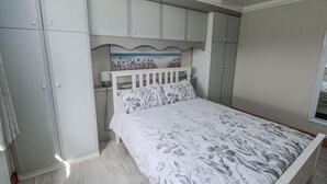 A bedroom with a bed, a nightstand, a wardrobe, and a painting above the bed. - Castle View (Carrowmoreknock)