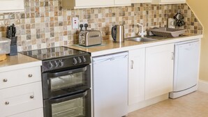 Une cuisine moderne avec des armoires blanches, une cuisinière en acier inoxydable, un lave-vaisselle et un dosseret carrelé.