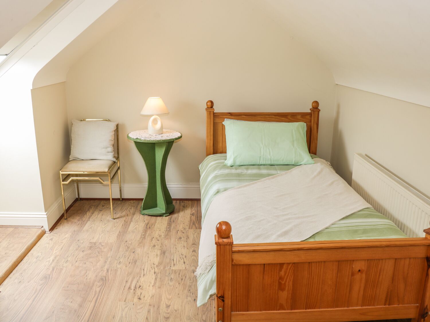 Ein Schlafzimmer mit einem Holzbett, einem Nachttisch mit Lampe, einem Sessel und einer Heizung.