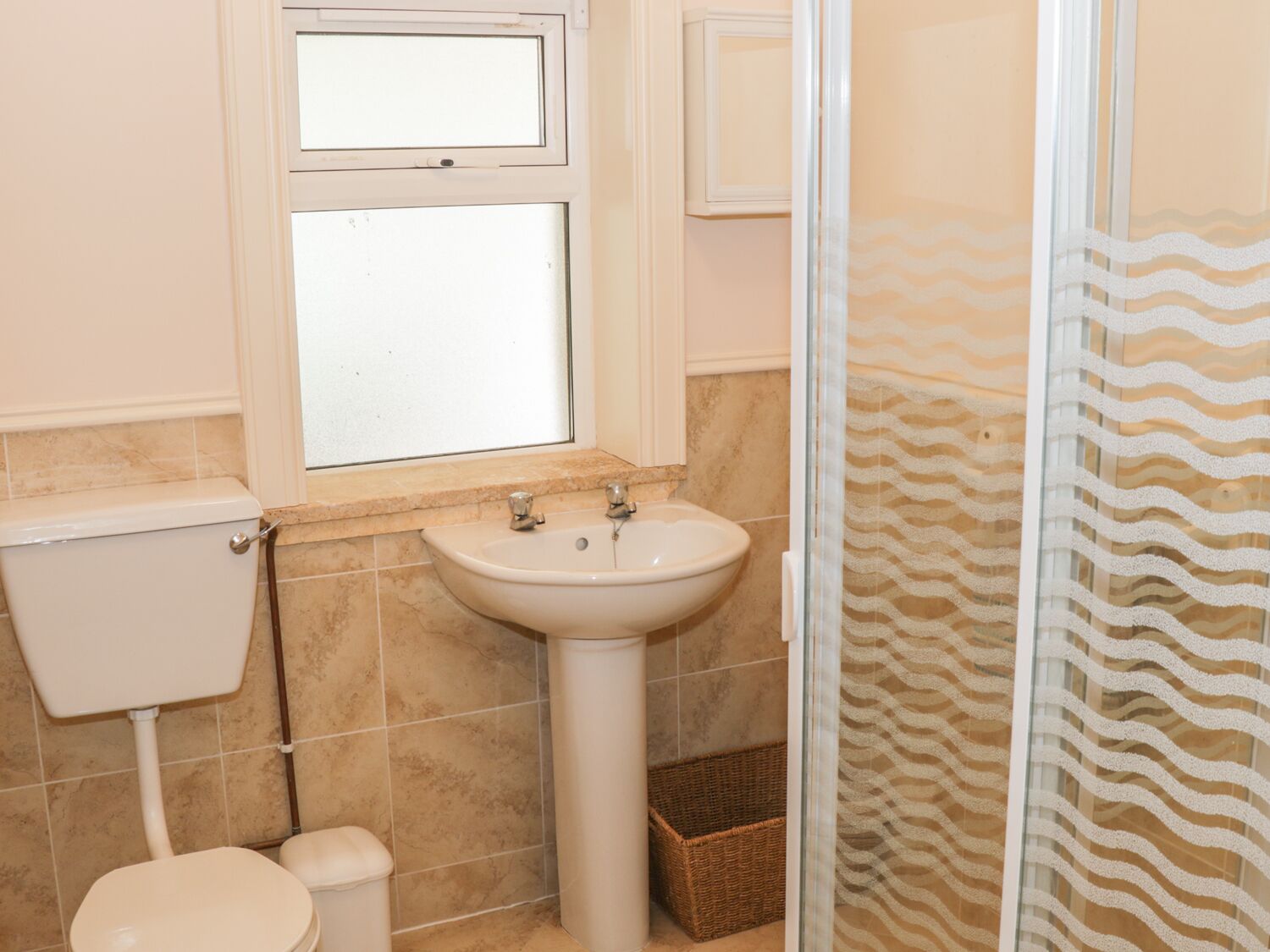 A bathroom with a toilet, sink, and window.
