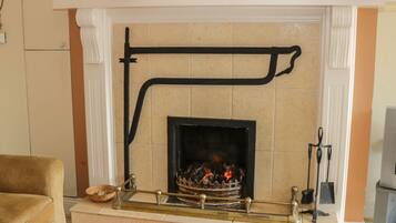 A living room with a fireplace, a sofa, and a mantelpiece with decorative items.