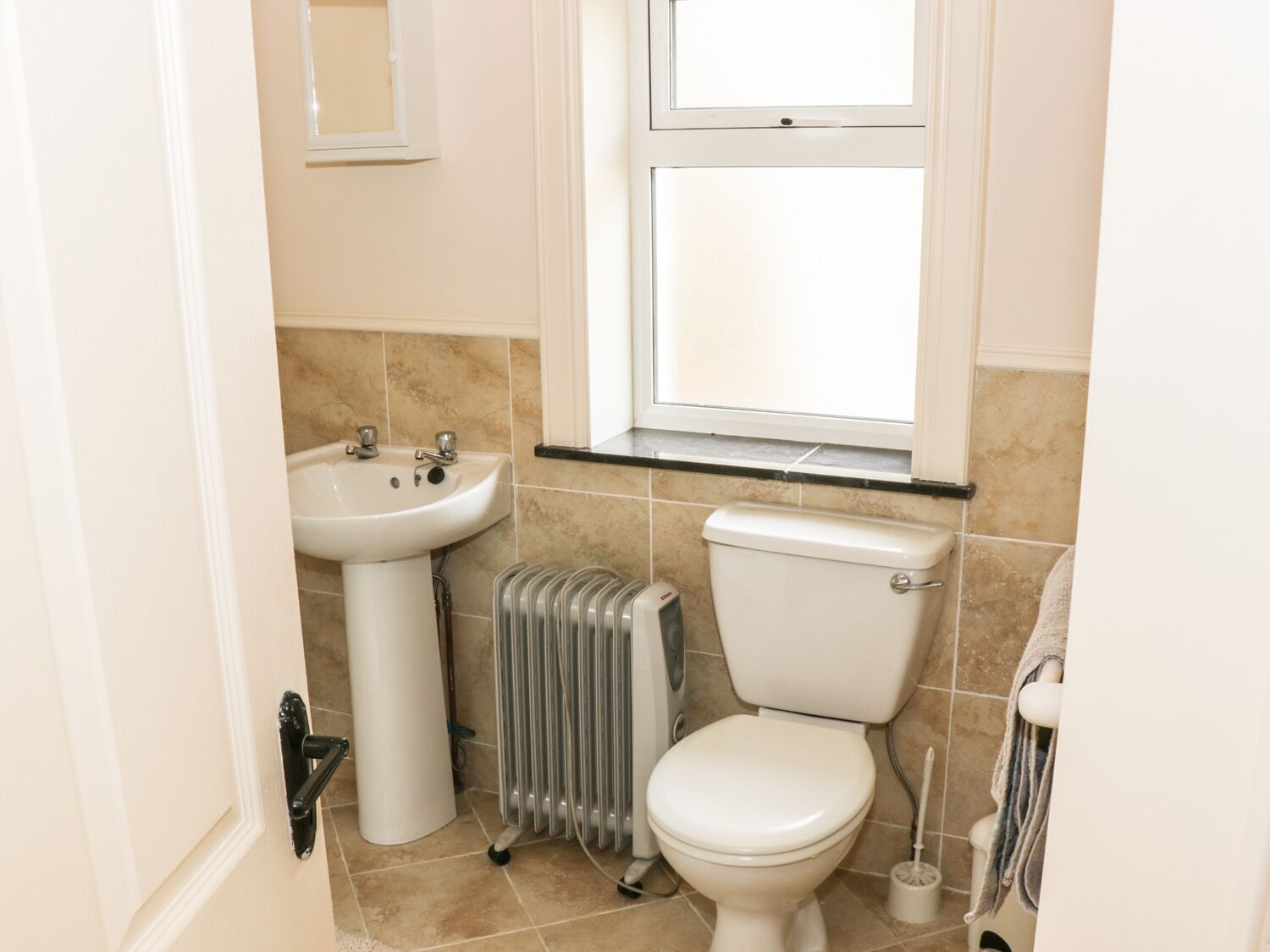 A small bathroom with a white sink, toilet, and radiator.