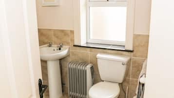 A small bathroom with a white sink, toilet, and radiator.