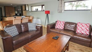 A living room with two brown leather sofas, a wooden coffee table, and a red floor lamp. - The Owl's Hoot (Tacumshane)