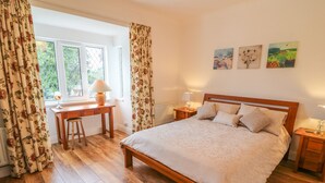 Une chambre avec un lit en bois, un bureau et une chaise, une fenêtre avec des rideaux et trois tableaux accrochés au mur.