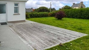 A residential property with a paved patio, a lawn, and a small garden area. - Ocean View (Ballinskelligs)