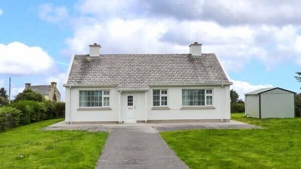 A single-story white house with a grey tiled roof, a front door, and a small porch. - Ocean View (Ballinskelligs)